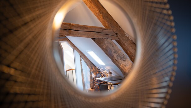Vista circular de una habitación con vigas de madera, una mesa y un farol colgante.