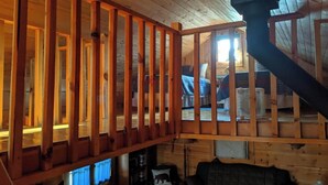 A cabin interior with a wooden deck, a staircase, and a cozy seating area. - Amish-Built Cabin in the Driftless Area (Boscobel)