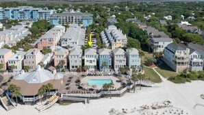 A coastal hotel with multiple buildings, a swimming pool, and a beach area.