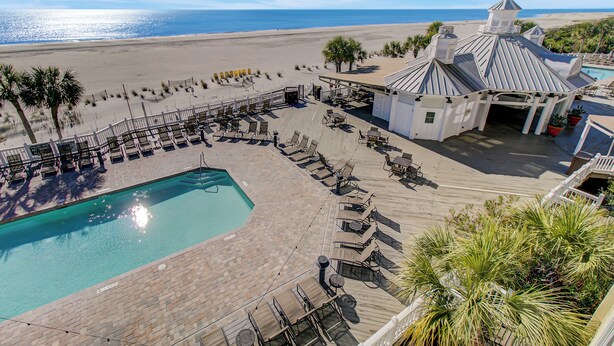 A pool area with lounge chairs and a small building with a unique roof design.