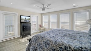 A bedroom with a bed, dresser, television, and ceiling fan.