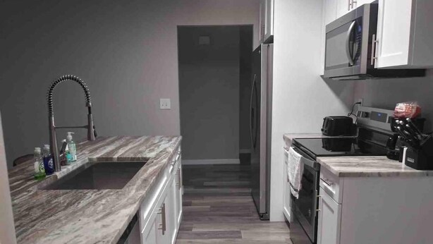 Una cocina moderna con encimera de mármol, electrodomésticos de acero inoxidable y suelo de madera.