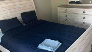 Un dormitorio con cama, cómoda, espejo y ventilador de techo.