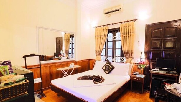 A hotel room with a bed, a desk, a chair, a TV, and a window with curtains. - A25 Hotel New Asean (Hanoi)