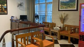 A hotel lobby with a checkered floor, wooden chairs, a reception desk, and artwork on the walls. - A25 Hotel New Asean (Hanoi)