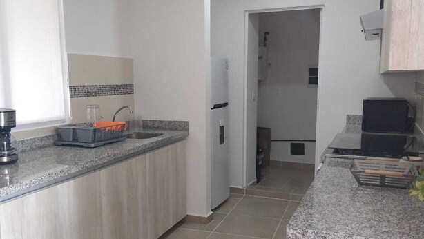 Una cocina moderna con encimera de granito, horno integrado y refrigerador.