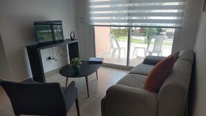 Una sala de estar con un sofá, una mesa de centro y un televisor sobre un mueble.