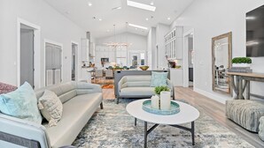 A spacious living room with a modern sofa, a coffee table, and a dining area in the background. - Luxury Gulf-Front Retreat. Heated Pool, Pet-Friendly.  (Cape San Blas)