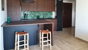 Eine moderne Küche mit dunklen Holzschränken, einer grünen Küchenzeile und einer zentralen Kochinsel mit Hockern.
