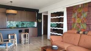 Ein modernes Wohnzimmer mit einer Couch, einem Holztisch und einer Küchenzeile mit Holzschränken und einer grünen Spritzschutzwand.