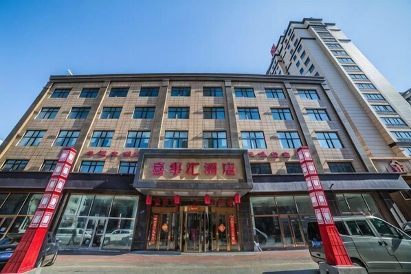 A multi-story hotel with a prominent entrance, large windows, and a clear sky. - Xishihui Hotel (Mishan)
