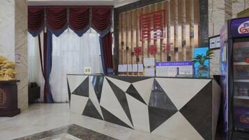 A reception desk with a geometric pattern, a red sign with Chinese characters, and a vending machine to the right.