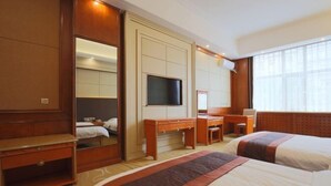 A hotel room with a large bed, a desk, a chair, a television, and a mirror. - Xishihui Hotel (Mishan)