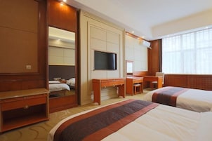 Una habitación de hotel con dos camas, un escritorio, una silla, un televisor y un espejo grande.
