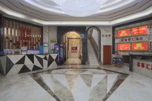A hotel lobby with a reception desk, a staircase, and a large chandelier. - Xishihui Hotel (Mishan)