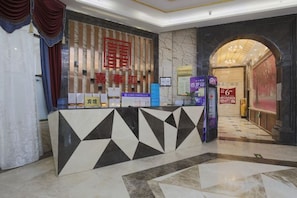 A hotel reception area with a reception desk, a digital information kiosk, and a marble floor. - Xishihui Hotel (Mishan)