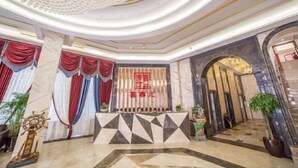 A hotel lobby with a reception desk, a decorative ceiling, and a geometric floor pattern. - Xishihui Hotel (Mishan)