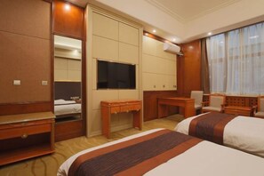 Ein Hotelzimmer mit zwei Betten, einem Schreibtisch, einem Stuhl, einem Fernseher und einem Kleiderschrank.
