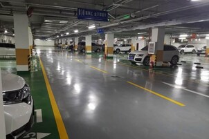 Un estacionamiento con varios niveles, autos estacionados en cada nivel, señalización clara y un piso limpio y bien conservado.