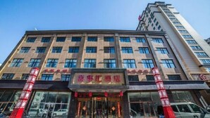 A multi-story hotel with a prominent entrance, large windows, and a clear sky. - Xishihui Hotel (Mishan)