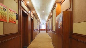 A hotel hallway with wooden paneling, a patterned carpet, and informational posters on the walls. - Xishihui Hotel (Mishan)