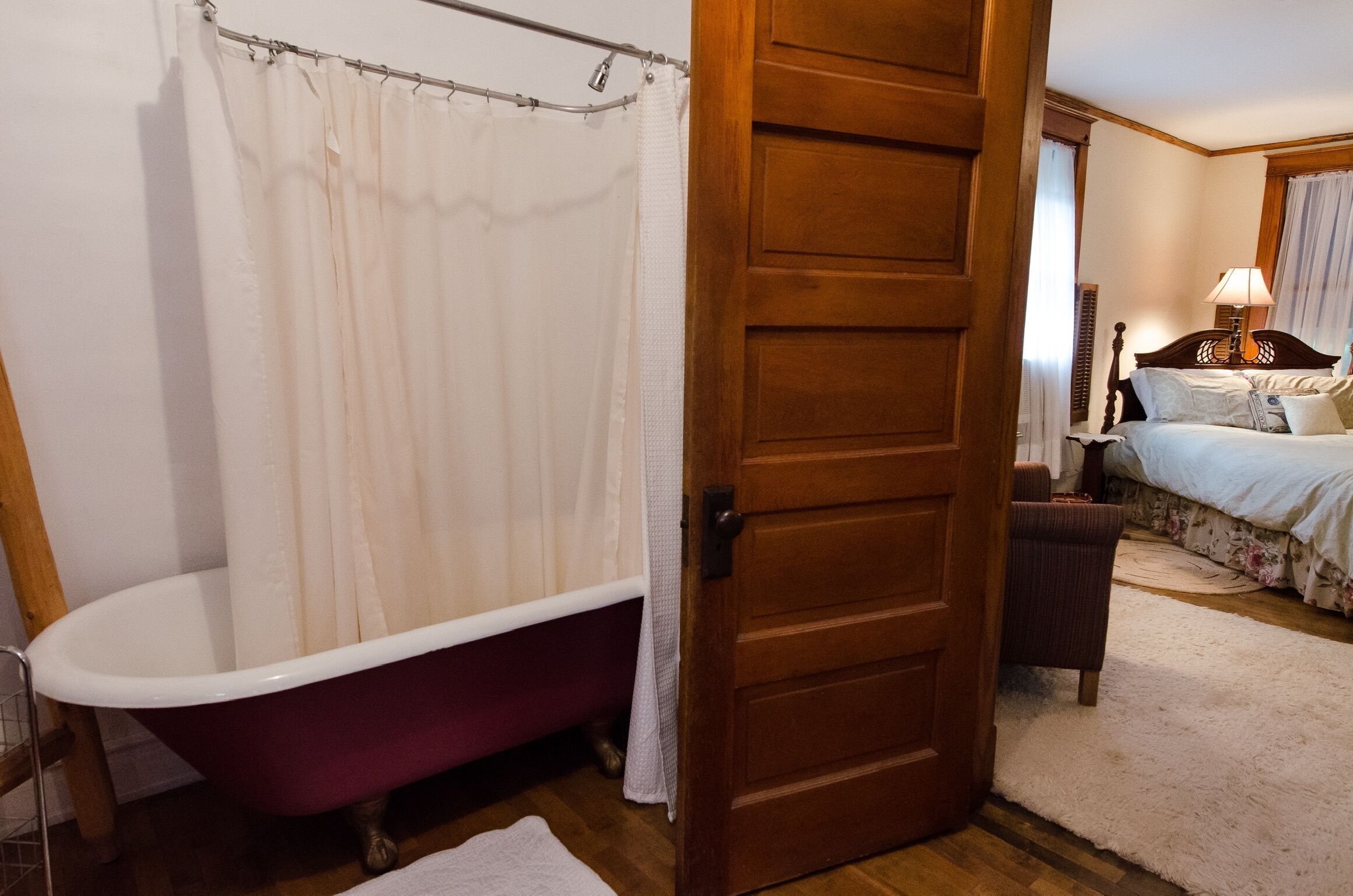 A bathroom with a clawfoot bathtub, a wooden door, and a shower curtain.