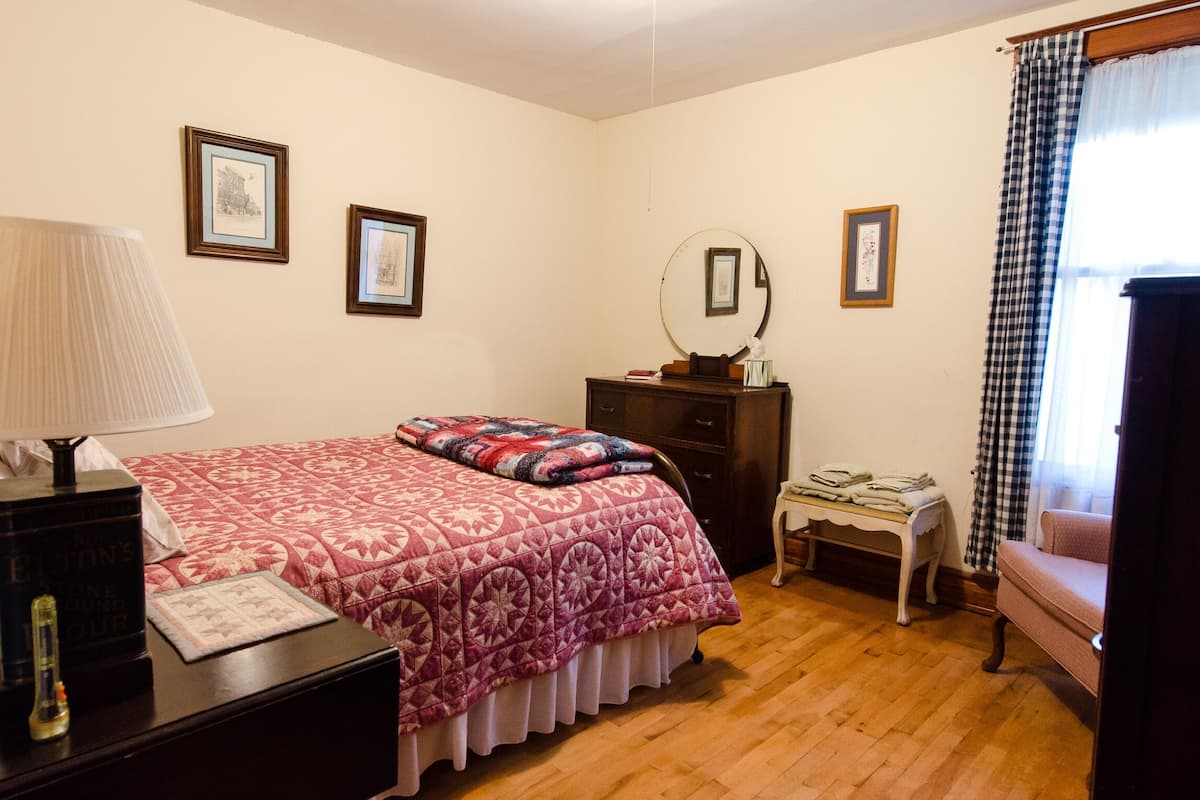 A bedroom with a bed, dresser, and a nightstand with a lamp.