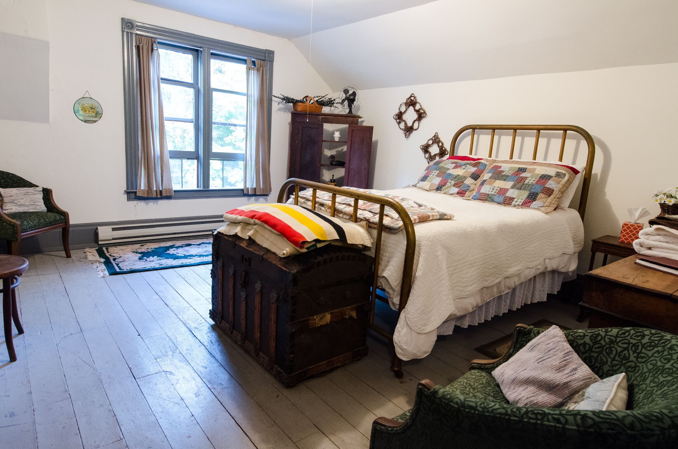 A bedroom with a bed, a dresser, a chair, and a window.