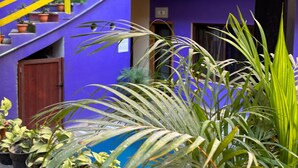 Un immeuble à plusieurs étages, avec une façade violette, des garde-corps jaunes et des décorations suspendues.