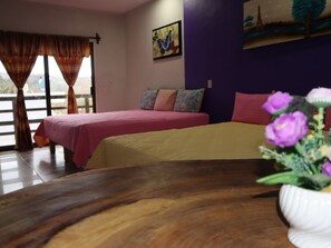 Un dormitorio con dos camas, una mesa de madera y un ventanal con cortinas.