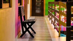 Un couloir d’hôtel avec un banc en bois, un mur vert et une porte portant le numéro 17.