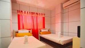 Habitación de hotel con dos camas individuales, televisión y aire acondicionado.