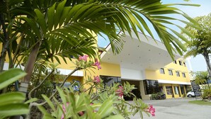 Un edificio amarillo de diseño moderno, con un acceso cubierto y una zona de estacionamiento.