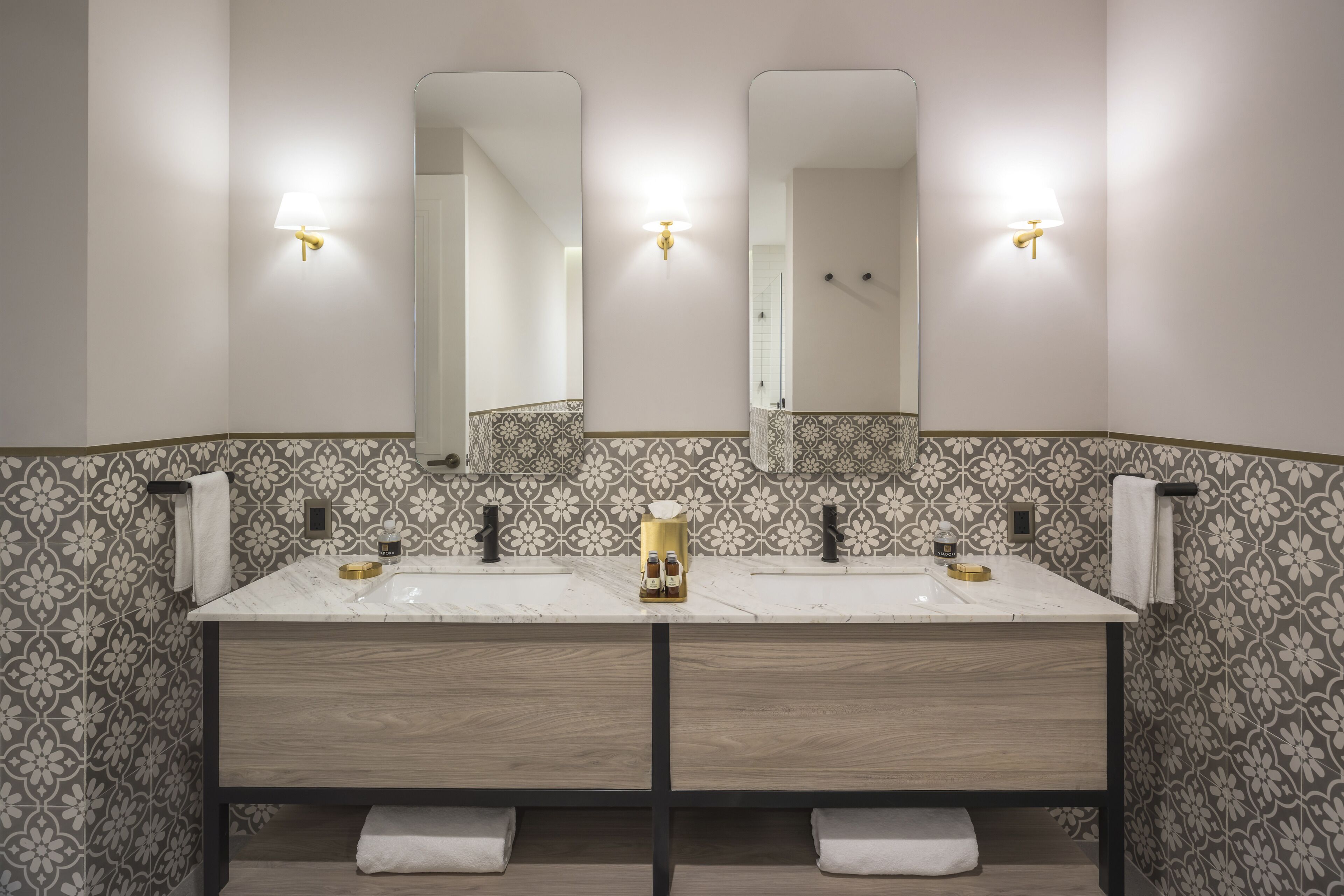 A modern bathroom with two sinks, a large mirror, and wall-mounted lights.