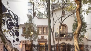 A building with a sign reading 'Casa Cleo by Viadora,' featuring ornate balconies, a wrought iron fence, and lush greenery. - Casa Cleo Boutique Stays by Viadora (Mexico City)