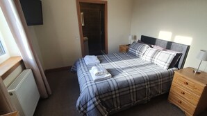 Un dormitorio con cama, cómoda, lámpara y radiador.