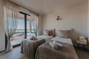 A hotel room with two beds, a view of the sea, and a teddy bear on a small table. - Lux Villa Core with amazing view and heated pool (Seget Donji)
