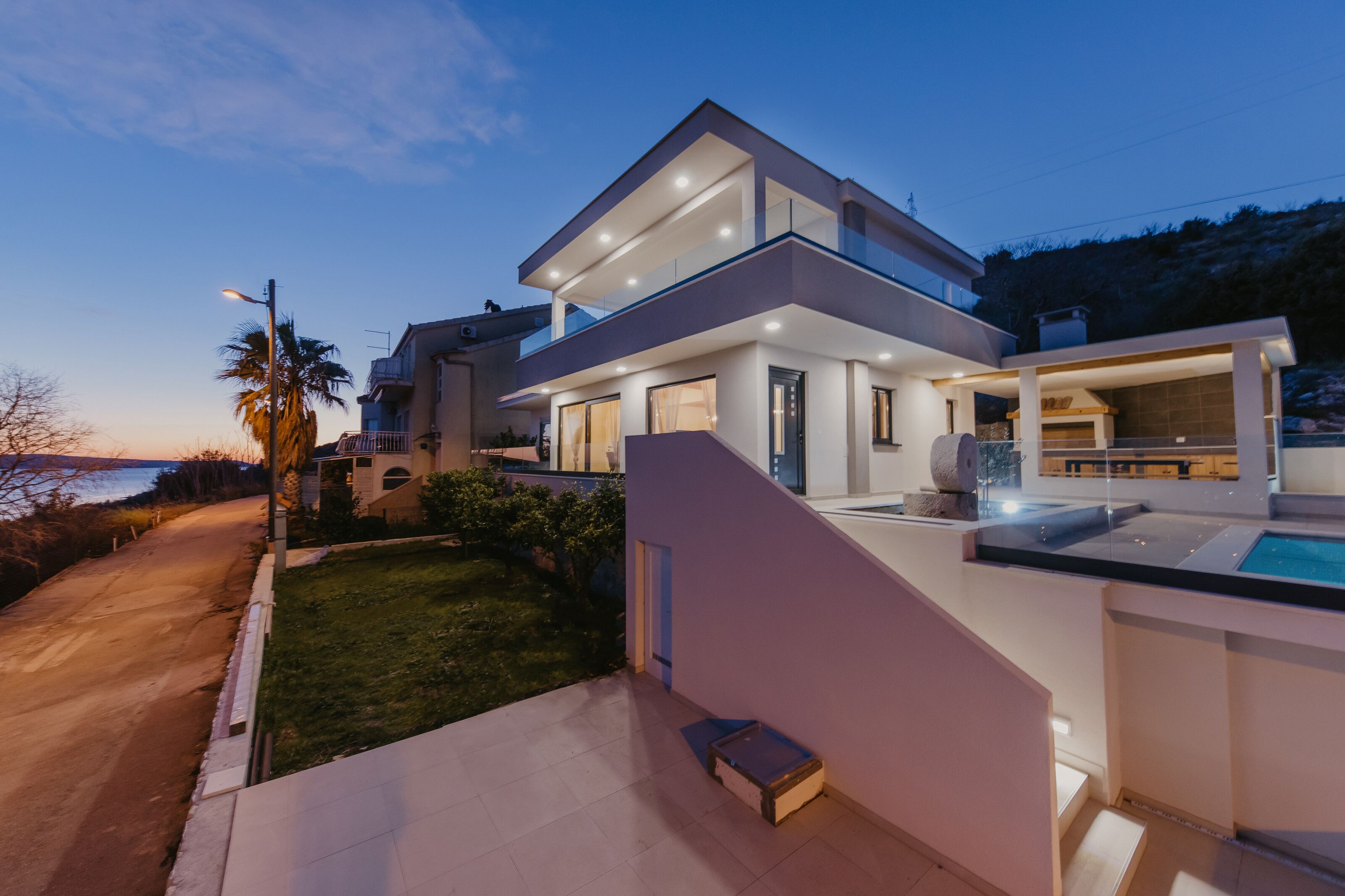 Une maison moderne à deux étages, dotée d’une piscine, de grandes fenêtres et d’une pelouse bien entretenue.