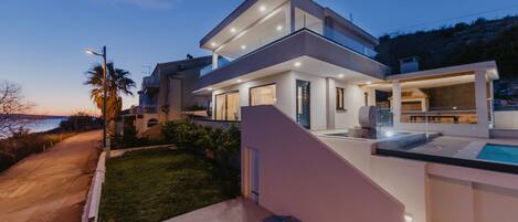 Una casa moderna de dos pisos con piscina, ventanas amplias y un césped bien cuidado.