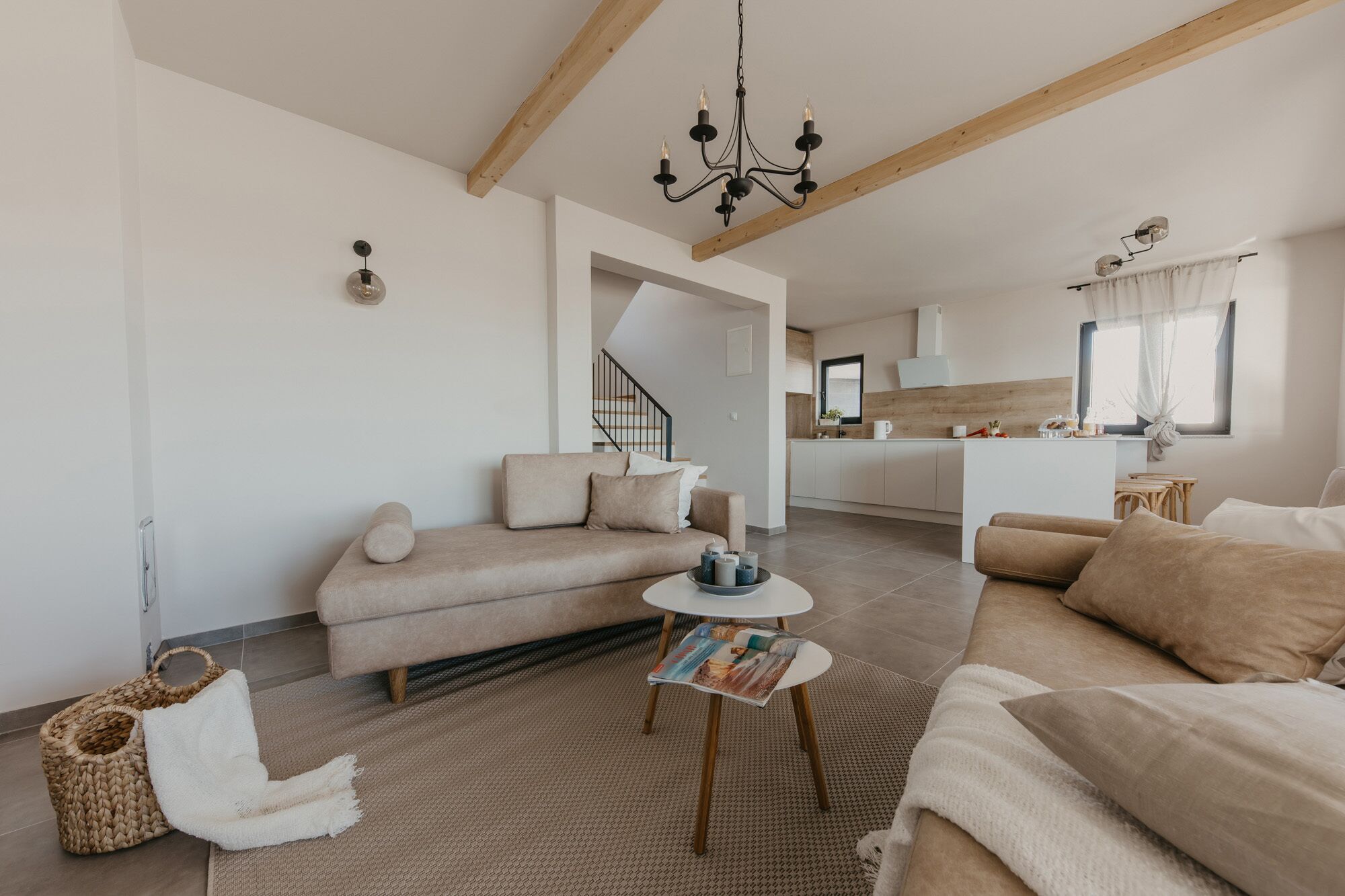 A modern living room with a sofa, a coffee table, and a kitchen in the background.