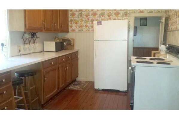 A kitchen with wooden cabinets, a white refrigerator, and a stove.
