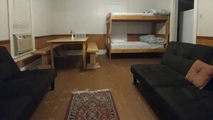 A room with two black sofas, a wooden table, a bunk bed, and a patterned rug. - Aunt Jane's Yellow House downtown Great for Events (Put-in-Bay)