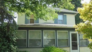 A two-story house with a large front window and a door. - Aunt Jane's Yellow House downtown Great for Events (Put-in-Bay)