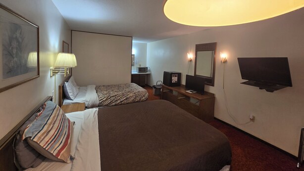 A hotel room with a large bed, a desk with a computer, a TV, and a lamp. - OYO Sandman Inn (Eagle Grove)