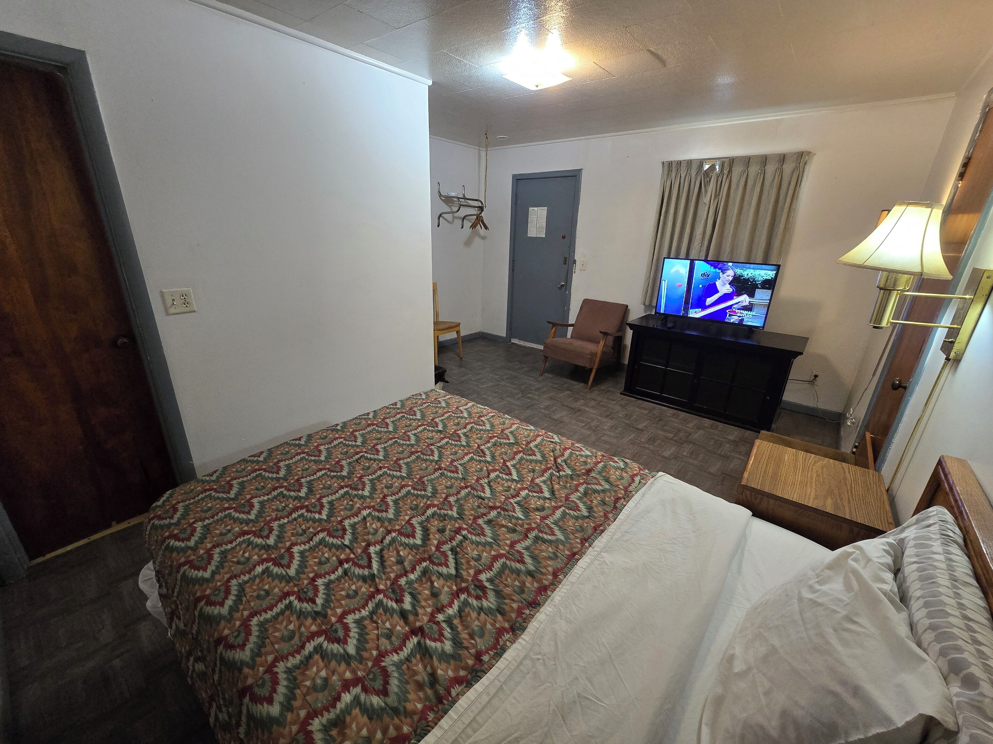 A hotel room with a bed, a television, a desk, and a chair.