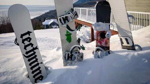 Zona nevada con varias tablas de snowboard apoyadas contra una estructura de madera.