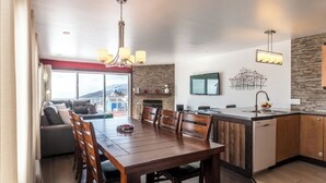 Cocina moderna con comedor, armarios de madera y un amplio ventanal con vistas panorámicas.