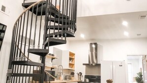 Et moderne køkken med en central ø, indbygget ovn og et rustfrit stål emfang.