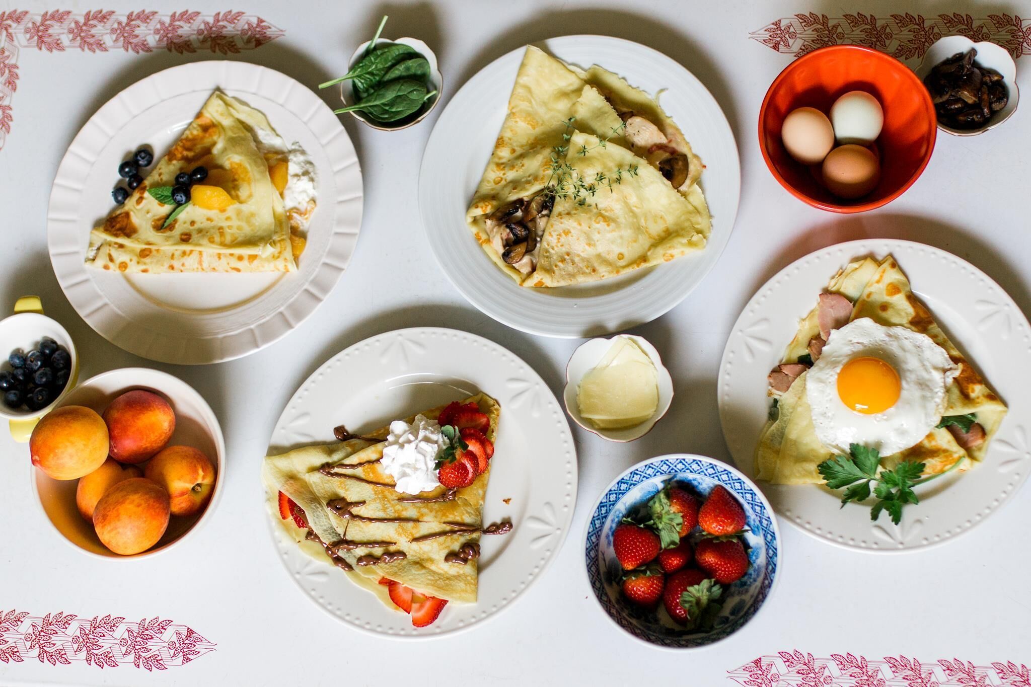 Une table garnie de divers aliments pour le petit-déjeuner, notamment des crêpes, des fruits et des œufs.