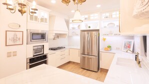Une cuisine moderne dotée d’appareils électroménagers en acier inoxydable, de meubles blancs et d’un lustre.